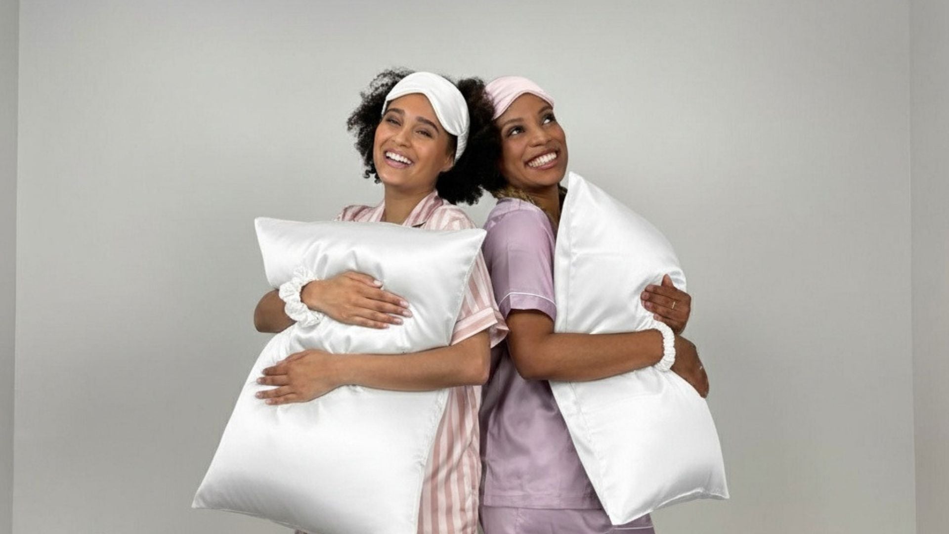 Models holding ivory silk pillowcases