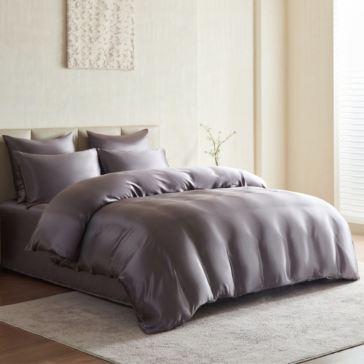 Gray silk bedding set on a bed in a bedroom with neutral decor