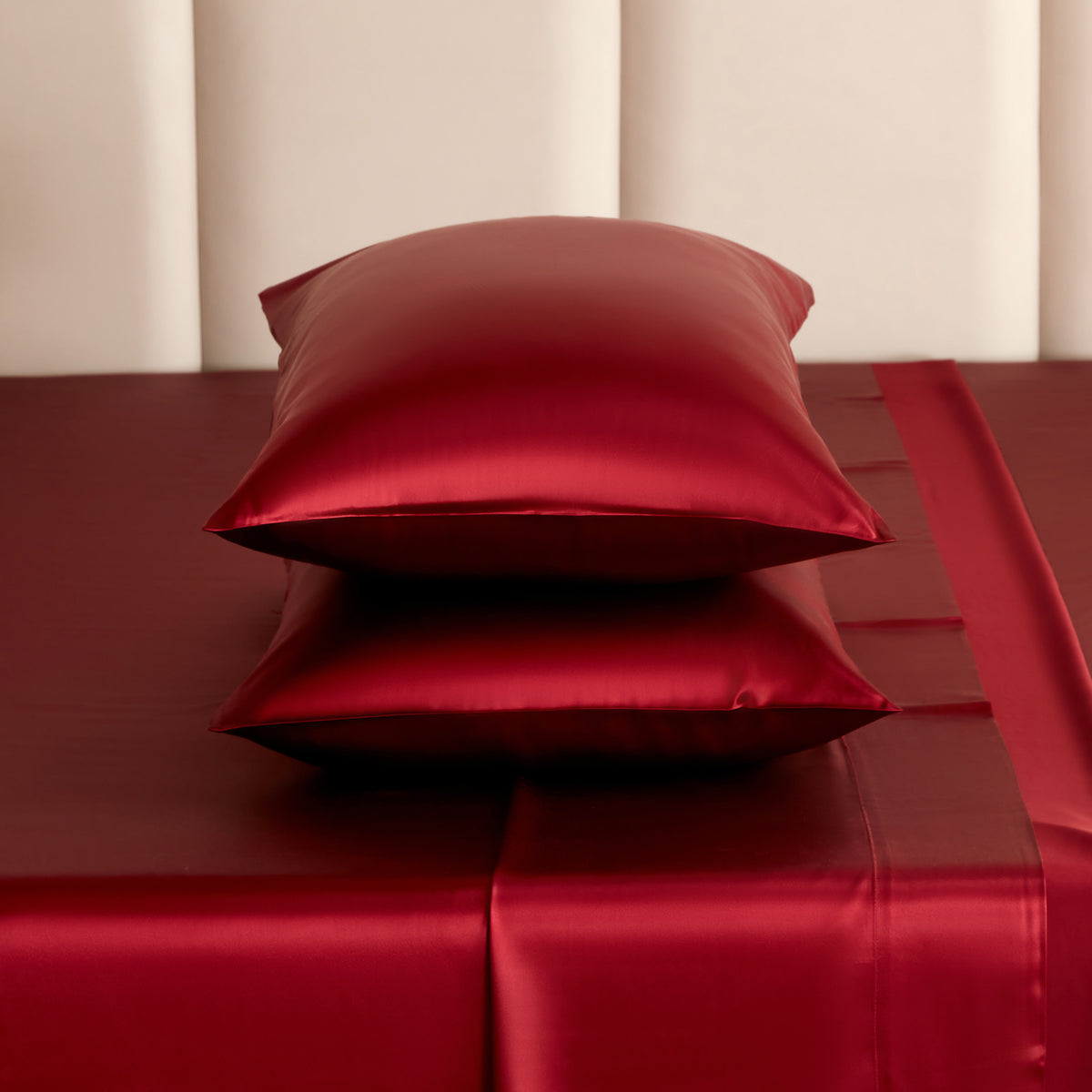 Stack of cabernet red Mulberry Park Silks pillowcases and sheets showcasing the smooth, lustrous sheen and rich color of 22 momme pure Mulberry silk bedding.