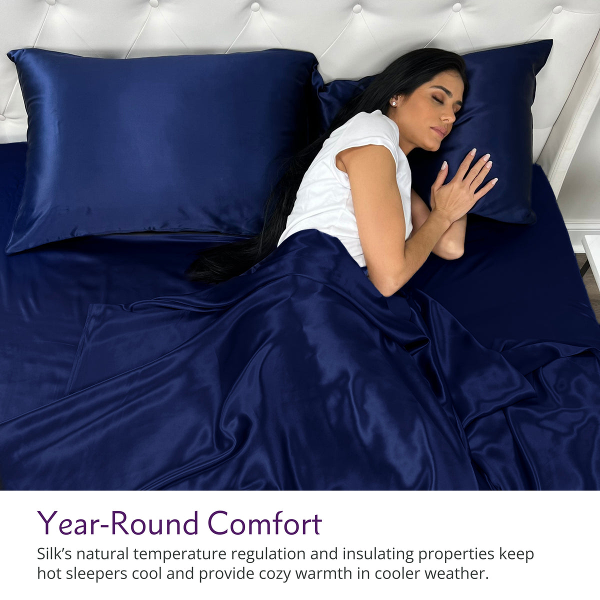 Woman sleeping under navy silk sheets and pillows with text about year-round comfort.