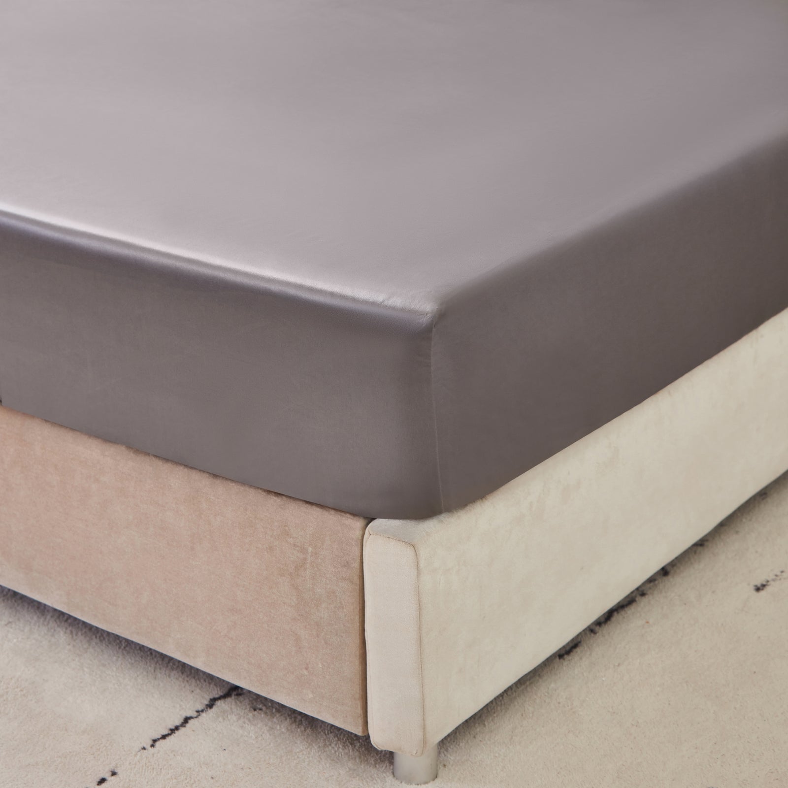 22 momme silk fitted sheet in Gunmetal on bed with upholstered headboard in a cozy bedroom setting