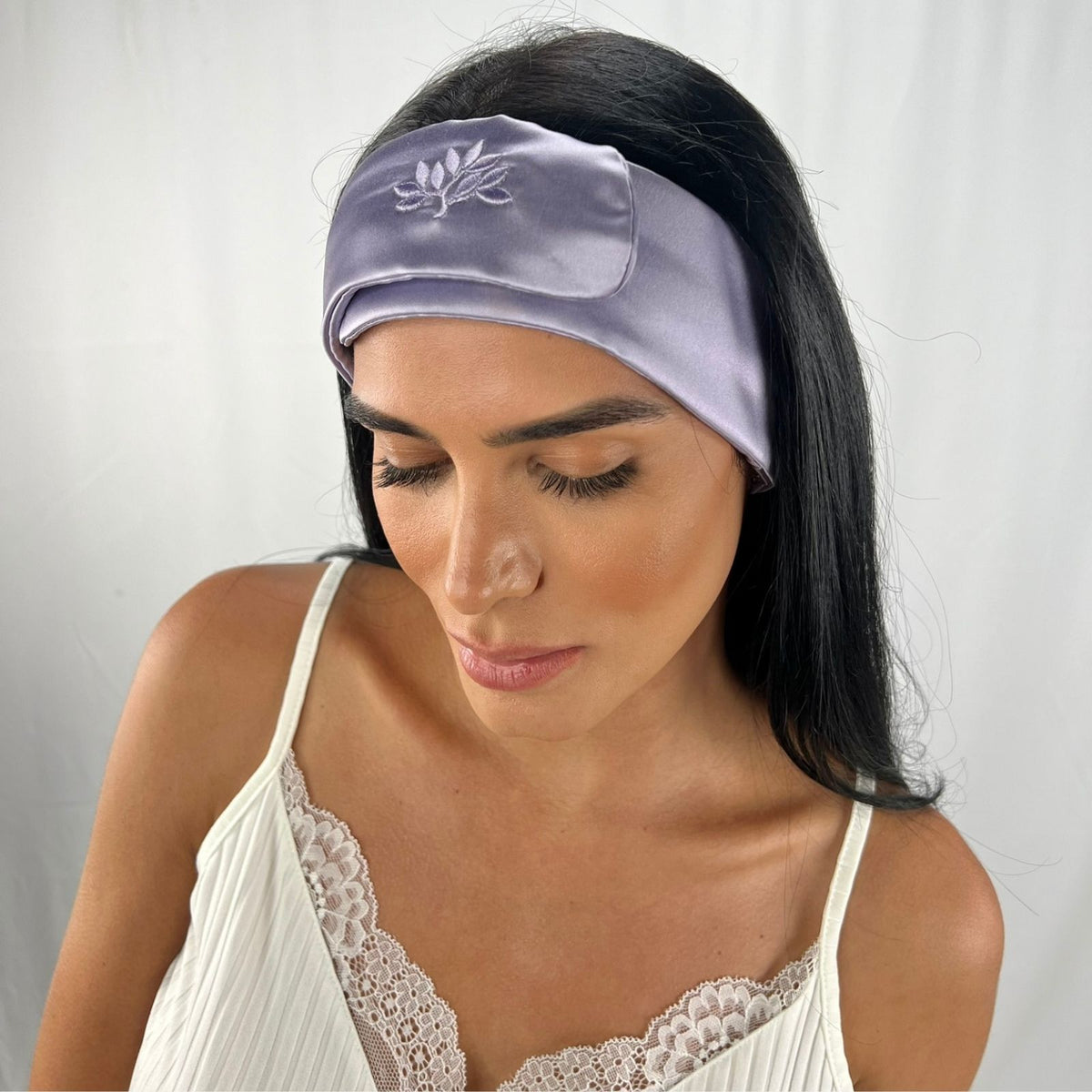 Woman with long dark hair in a Mulberry silk beauty band and white lace-trimmed camisole, looking down.