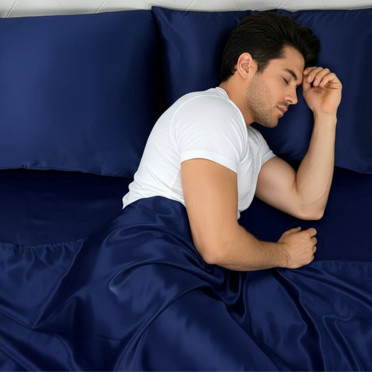 Young man resting on a bed with Mulberry Park Silks' 30 Momme Silk Pillowcase in navy, showcasing its luxurious, smooth texture.