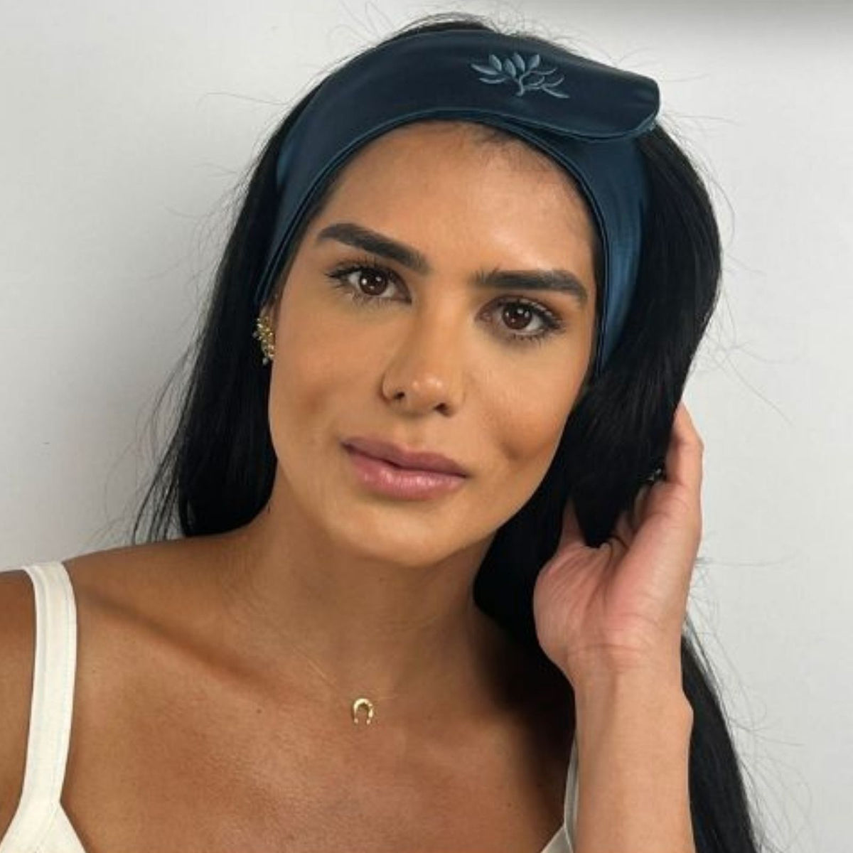 Woman wearing a dark blue mulberry silk headband with an embroidered leaf design.